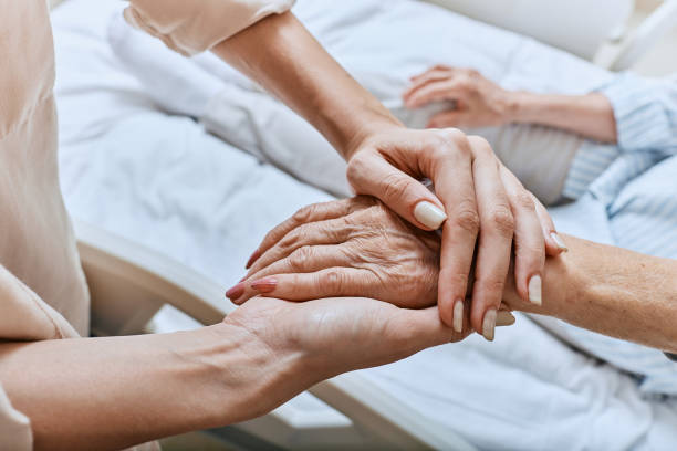 Caregiver gently holding a patient’s hands in a hospice setting