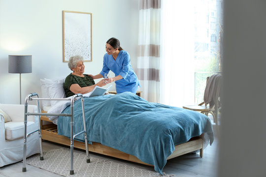 Hospice caregiver assisting a patient in bed